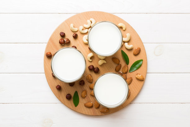 集或收集各种纯素牛奶杏仁，腰果，在桌子的背景。素食植物奶和原料，俯视图图片下载