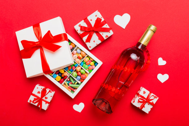 一瓶红酒在彩色背景情人节与礼物和巧克力。心形与巧克力礼盒顶部视图与复制空间图片下载