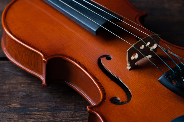 小提琴，一个美丽的小提琴在质朴的木材上的细节，低调风格的照片，黑色背景，选择性聚焦。图片下载