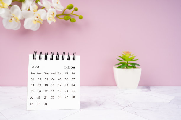 2023年10月的台历和白色兰花一个粉红色的背景。图片下载