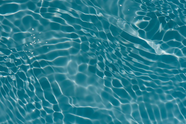蓝蓝的水面上泛起涟漪。散焦模糊透明蓝色透明平静水面纹理与飞溅和气泡。水波与闪亮的图案纹理背景。图片下载