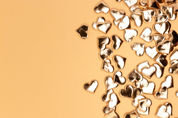 粉红色背景上的金色心形纸屑。图片下载