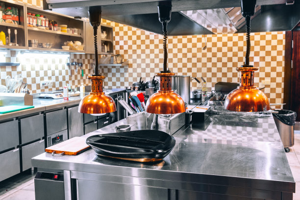 没有人的餐厅厨房。咖啡厅的厨房里没有人。概念-餐厅的工作已经停止。配有镀铬设备的小餐厅厨房。餐桌上的盘子和产品。图片下载