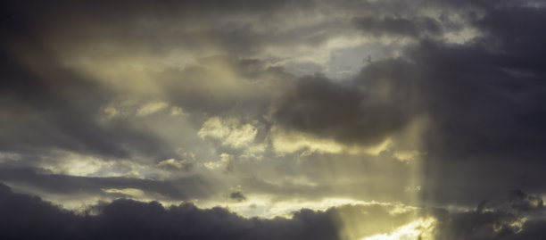 阳光透过阴霾在蓝天上戏剧性的金色日落背景暮光乌云橙光傍晚纹理景观背景自然全景明亮。图片下载