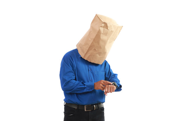 一个拿着纸袋的商人在看或检查他的手表图片下载