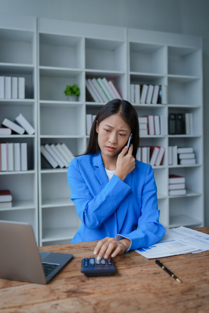 忙碌的女商人穿着西装忙着工作，工作狂一边坐着工作一边清理文件，用智能手机打电话，听着熙熙攘攘，忙碌的概念。图片下载