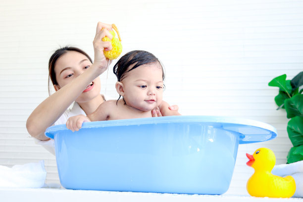 快乐的蹒跚学步的婴儿在浴室里玩泡泡浴，妈妈在浴缸里给孩子洗澡，妈妈在浴缸里给她的小女孩、女儿、孩子洗澡，童年和父母的照顾。图片下载