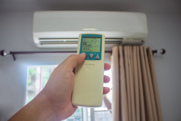 男子用手遥控打开卧室的空调降到了25摄氏度。健康理念和节能。图片下载
