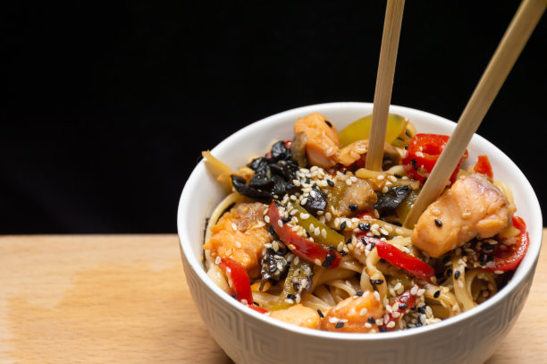 在一盘面条上配上三文鱼、蔬菜和芝麻图片下载