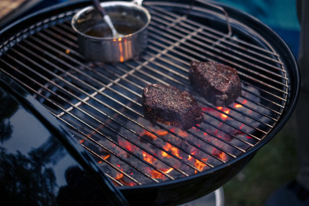 美味的牛排和肋眼烧烤股票照片。酱汁撒在肉上。烤架下面冒出了火图片下载