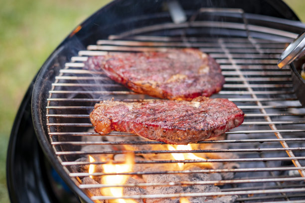 美味的牛排和肋眼烧烤股票照片。酱汁撒在肉上。烤架下面冒出了火图片下载