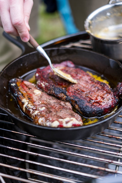 美味的牛排和肋眼烧烤股票照片。酱汁撒在肉上。烤架下面冒出了火图片下载