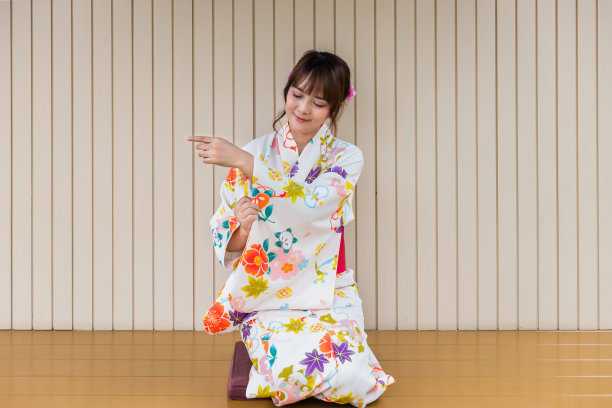 穿着传统和服的年轻女子坐在以花园为背景的日式茶具屋里图片下载