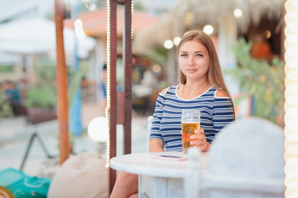 在海滩咖啡馆喝啤酒的女人的画像图片下载