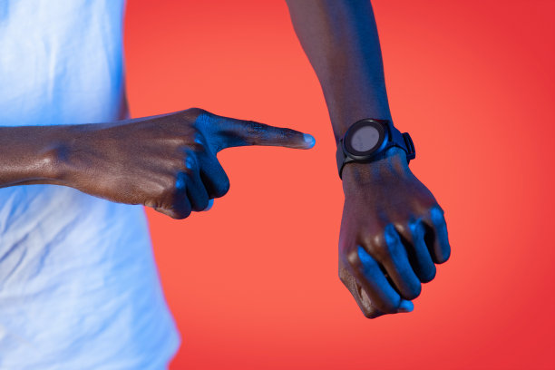 身穿霓虹灯的黑人手持智能手表，红色背景图片下载