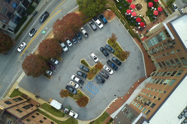 鸟瞰许多五颜六色的汽车停在公寓楼后院的停车场上。住宅公寓前的车辆停放处图片下载