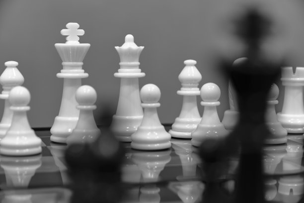 白色棋子的背景是黑色模糊的棋子。图片下载