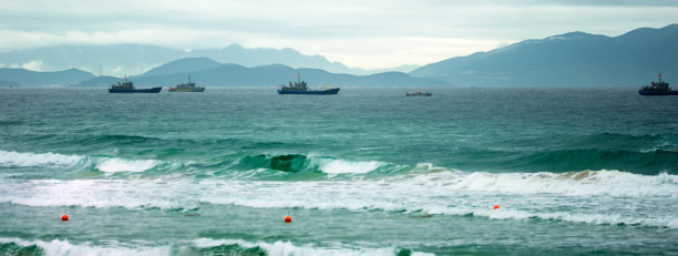 风景如画的海岸。全景景观渔船，山脉和美丽的多云的天空在日落。图片下载