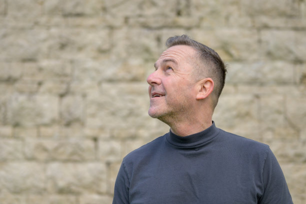 白发男子站在墙前图片下载