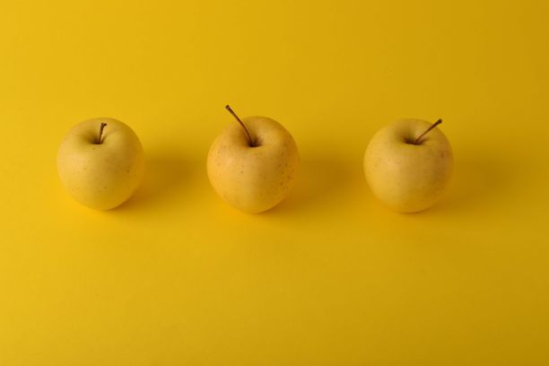 三个苹果排列在一个视觉上吸引人的组成在黄色的背景图片下载