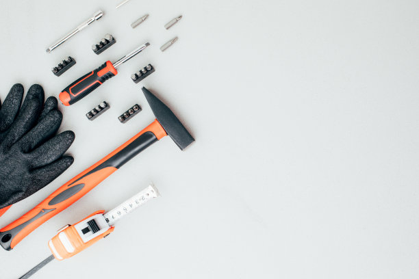 一套工作工具，一个锤子，一个螺丝刀，一个带着工作手套的灰色混凝土背景上的回答插座图片下载