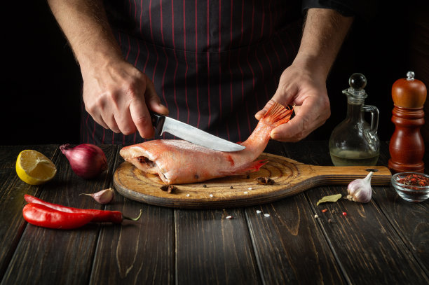 厨师在旅馆的厨房里准备鱼馅饼。在深色背景下烹饪鱼的概念。欧洲菜图片下载