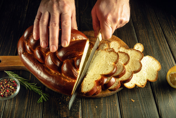 晚餐前由厨师亲手将美味的新鲜面包或卡拉什切片。健康食品或熟食概念图片下载