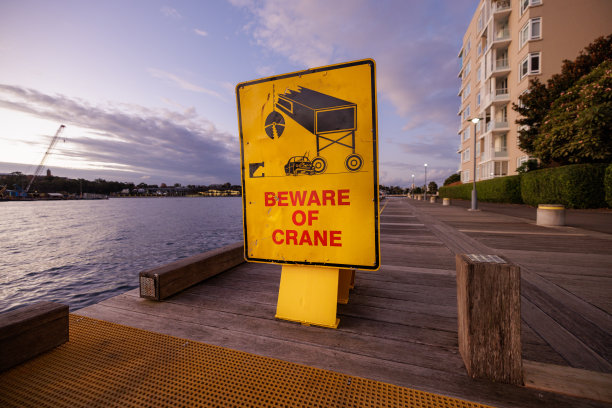 海边码头上的黄色“小心起重机”标志图片下载