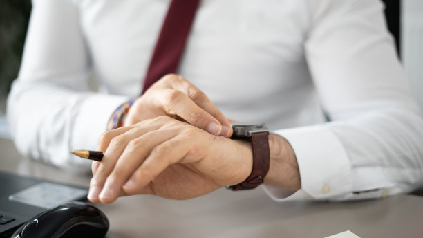 商人在办公室工作时看着他的智能手表图片下载