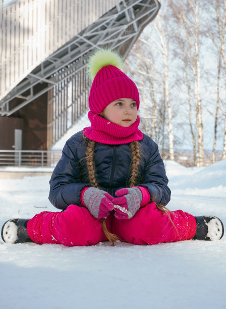 冬天，一个穿着冬衣的女孩坐在雪道上。在冬天漫步图片下载