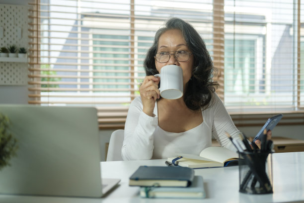 一幅冷静的老年妇女的画像，她喝着早晨的咖啡，看着窗外。图片下载