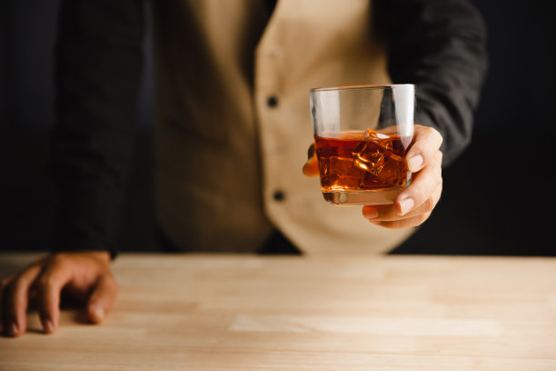 在酒吧或餐馆里拿着威士忌酒杯的年轻人。图片下载