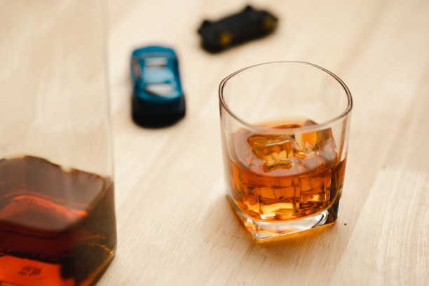 一杯加冰的威士忌放在吧台的桌子上和车钥匙上图片下载