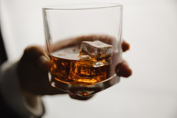 在酒吧或餐馆里拿着威士忌酒杯的年轻人。图片下载