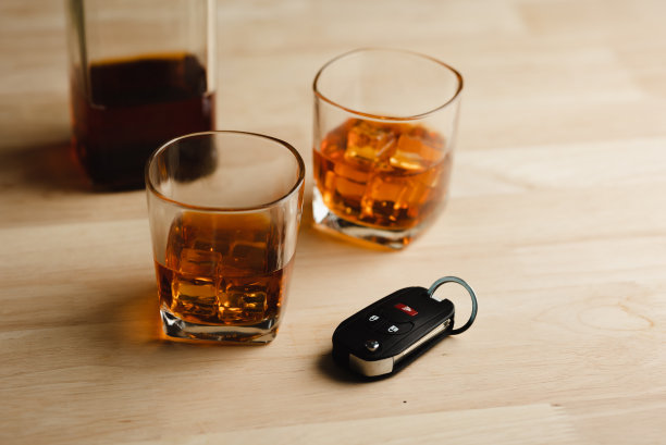 一杯加冰的威士忌放在吧台的桌子上和车钥匙上图片下载