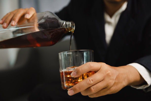 在酒吧或餐馆里拿着威士忌酒杯的年轻人。图片下载