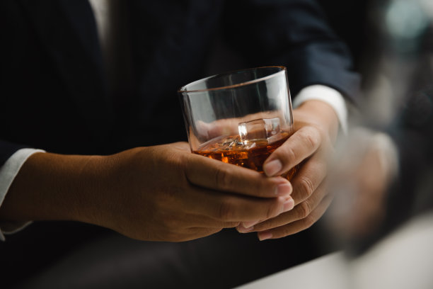 在酒吧或餐馆里拿着威士忌酒杯的年轻人。图片下载