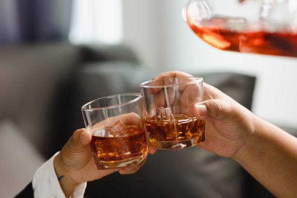 在酒吧或餐馆里拿着威士忌酒杯的年轻人。图片下载