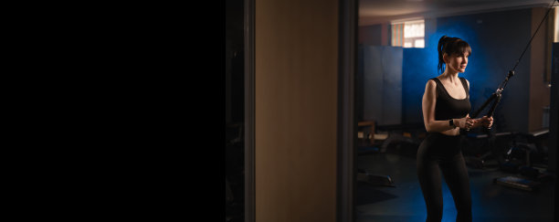 健身女性在健身房用绳子在机器上锻炼她的三头肌。运动、锻炼和人的概念。横幅。图片下载