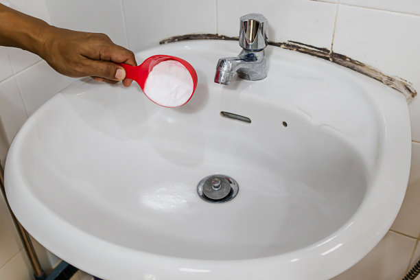 倒小苏打来清除家里水槽和排水管里的堵塞。图片下载