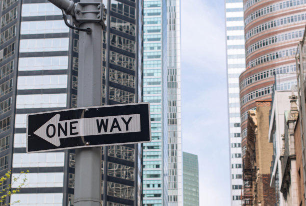 黑色的单行道标志安装在高层建筑的旁边图片下载