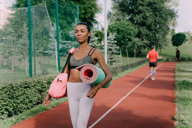 年轻苗条的非洲女性穿着运动服，手里拿着训练包和垫子去锻炼图片下载