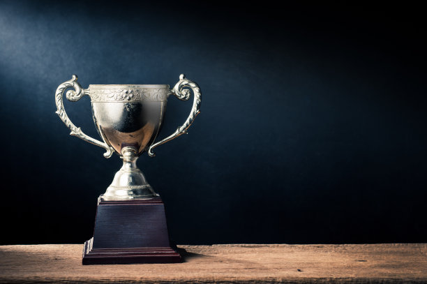 静物摄影:旧奖杯在旧木板与灯光在艺术黑暗的背景图片下载