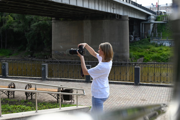 一位手持相机的女摄影师走在城市的街道上图片下载