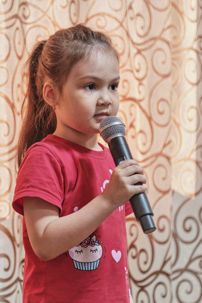 可爱害羞的小亚洲女孩在家里拿着麦克风的肖像。图片下载