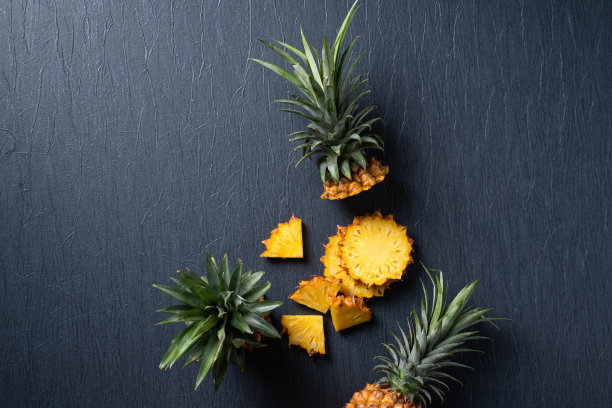 新鲜切菠萝与热带树叶在深蓝色的背景。图片下载