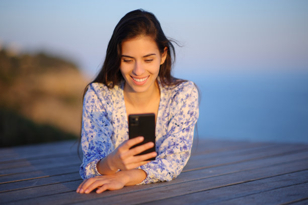 海滩上玩手机的快乐女人图片下载