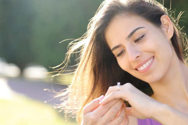 幸福的未婚妻在公园里看着订婚戒指图片下载