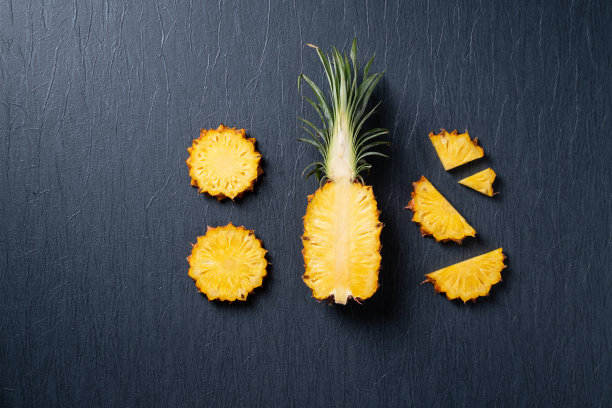 新鲜切菠萝与热带树叶在深蓝色的背景。图片下载