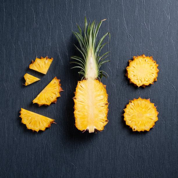 新鲜切菠萝与热带树叶在深蓝色的背景。图片下载